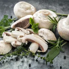 Świeże pieczarki, niektóre pokrojone, z ziołami i pieprzem. Odkryj ich bogate pieczarki wartości odżywcze.